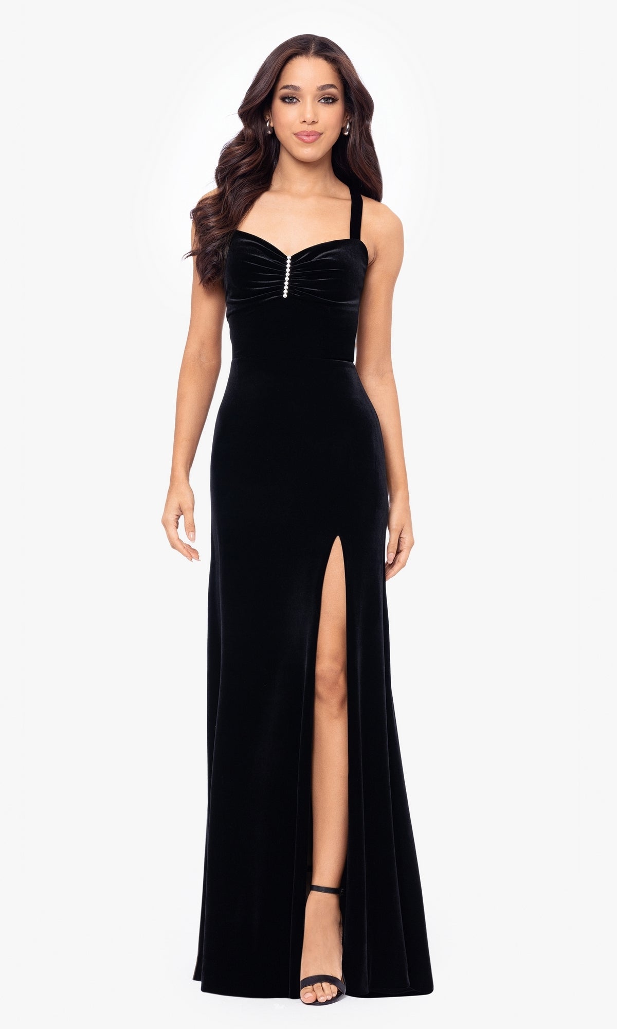 A woman stands facing forward in the Simple Long Velvet Prom Dress, Blondie Nites 5171BN—a black gown with a front slit, wide straps, and a sweetheart neckline.
